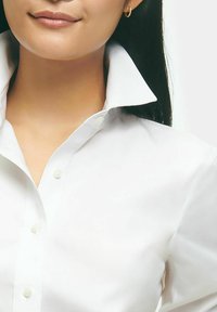 White button-up shirt with a structured collar and soft texture. Features a classic design with subtle buttons along the front.