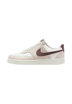 Basket basse en daim blanc et beige clair avec un swoosh Nike marron, des lacets blancs et une semelle blanche plate.