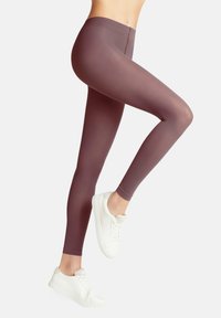 Leggings bordeaux con una superficie liscia e elasticizzata, caratterizzati da una vita alta e una vestibilità aderente, abbinati a sneakers bianche in tela.