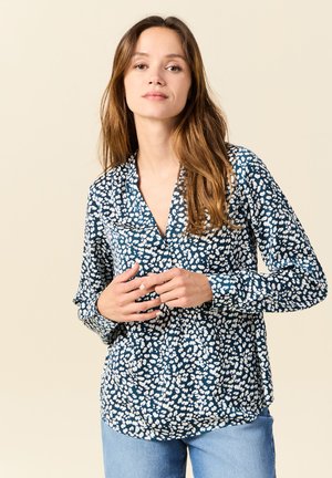 Blusa azul marino con un patrón floral blanco, escote en V, mangas largas y corte holgado. La tela parece suave y ligera.