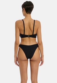 Conjunto de bikini negro que presenta un bralette texturizado con tirantes ajustables y una parte inferior de tiro alto a juego. La vista trasera muestra los detalles.