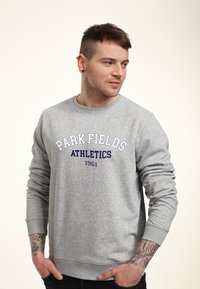 Szara bluza z okrągłym dekoltem, z napisem "PARK FIELDS ATHLETICS 1961" w białych i ciemnoniebieskich literach na przodzie.