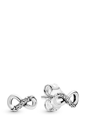 Strieborné náušnice v tvare nekonečna s lesklým povrchom, so šnúrou malých priehľadných kryštálov pozdĺž jednej strany. Sú súčasťou aj motýlikové zarážky.