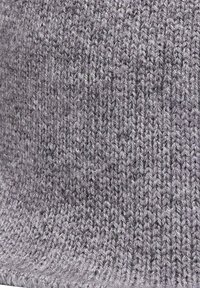 Gorro de punto gris hecho de hilo suave, con un patrón texturizado y un dobladillo enrollado. Diseño ligero y flexible.