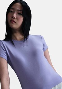 Lila kortearm fitted t-shirt gemaakt van gladde stof, met een klein wit Nike-logo op de borst en een ronde halslijn.