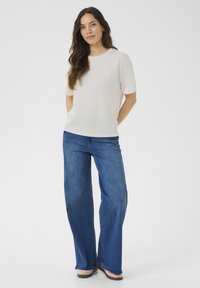 Hvid kortærmet T-shirt parret med brede blå denim jeans. Glat stof, afslappet pasform og en enkel, klassisk silhuet.