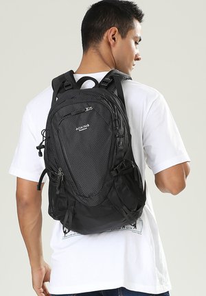 Zaino nero realizzato in materiale texturizzato, con una forma strutturata, scomparti con cerniera, spallacci regolabili e chiusure con coulisse.