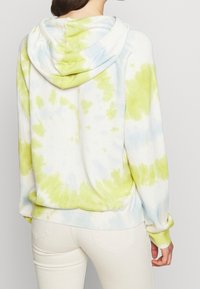 Hoodie i tie-dye-mönster med nyanser av grönt och blått, tillverkad av mjukt tyg med ribbade ärmslut och nederkant.