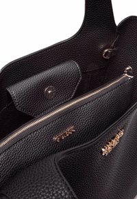 Bolso tote de cuero negro texturizado con un cierre de cremallera en tono dorado, solapa de bolsillo central y un logo visible en el interior.