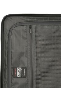 Gray suitcase interior featuring mesh and solid fabric compartments, dual zippers, and a label with care instructions. Durable material.
