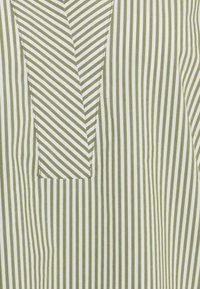 Tela a rayas verde y blanca con un diseño de bolsillo en zigzag. Las rayas son verticales, varían en ancho y tienen una textura suave.