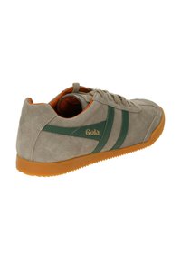 Zapatilla de gamuza gris con rayas verdes y logo dorado. Cuenta con una suela de goma en naranja y un acabado texturizado para mayor agarre.