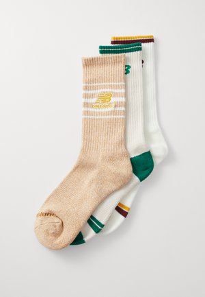 Trois paires de chaussettes : une marron clair avec deux rayures, une blanche avec des accents verts et bourgogne, et une blanche unie. Tissus texturés.