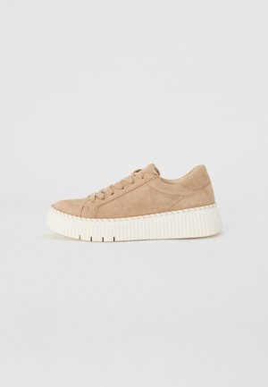 Beige suede sneakers with round toe, lace-up design, textured side panels, and a thick, ribbed cream sole.