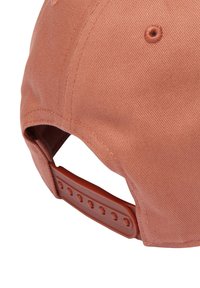 Gorra marrón con una textura de tela suave, visera curvada y correa de plástico ajustable con múltiples muescas para el tamaño.