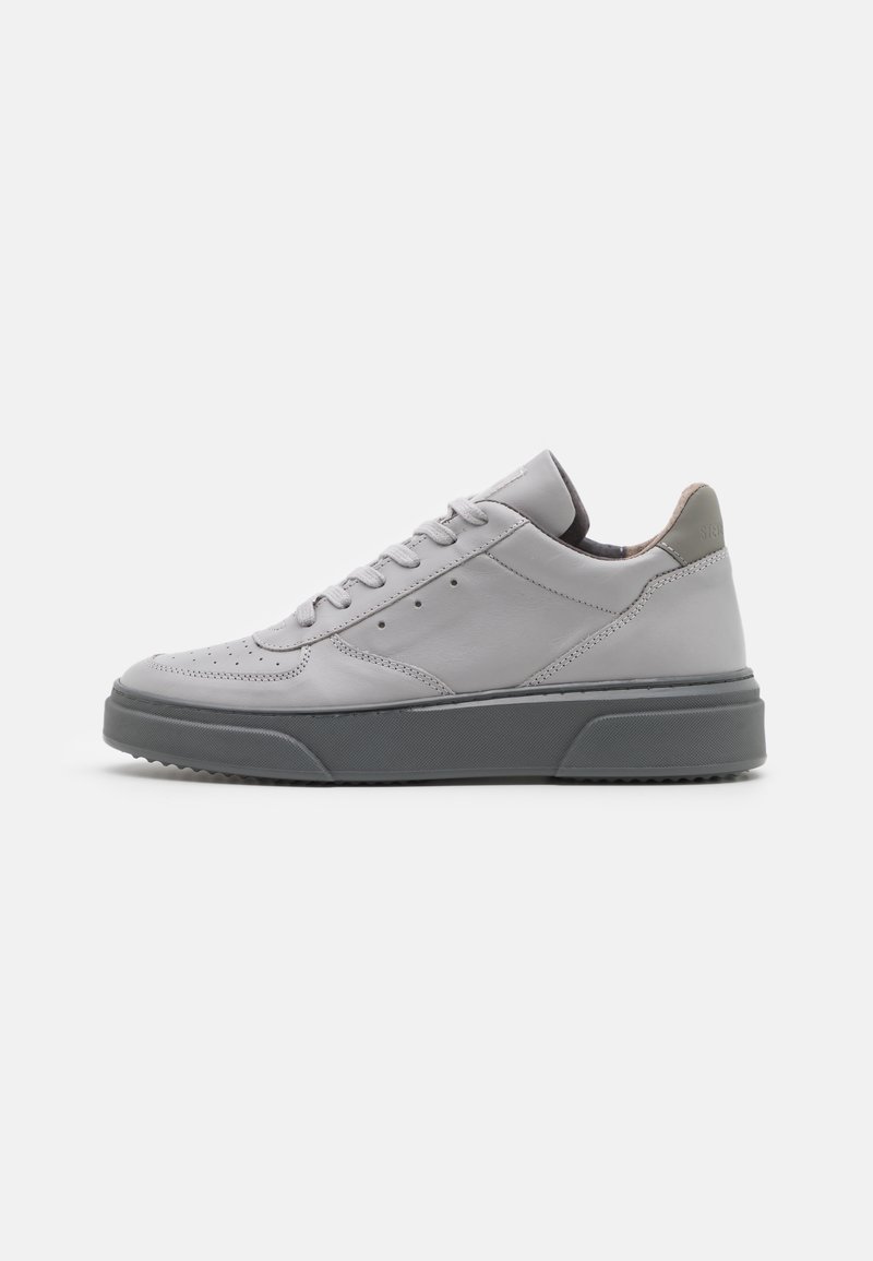 Graue Leder-Sneaker mit glatter Oberfläche, niedrigem Profil, kontrastierender dunkelgrauer Gummisohle und minimalistischem Design, das dezente Perforationen umfasst.