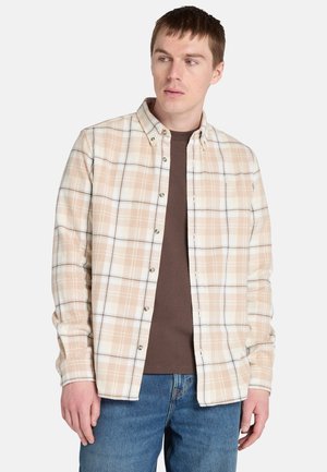 Camisa de cuadros clara en beige, blanco y marrón, con cuello estándar y mangas largas, superpuesta a una camiseta marrón.