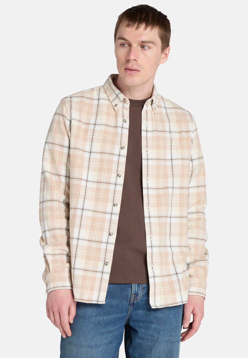Camisa de cuadros clara en beige, blanco y marrón, con cuello estándar y mangas largas, superpuesta a una camiseta marrón.