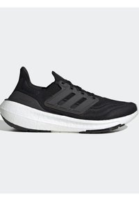Chaussure de course Adidas Ultraboost noire avec semelle blanche coussinée, tige en maille et trois bandes latérales noires sur fond gris clair.