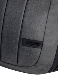 Zaino in tessuto grigio con finitura testurizzata, forma slanciata e una etichetta rettangolare nera con il logo "American Tourister."