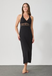 Camisón negro con una forma ajustada, que presenta un corpiño de encaje y un diseño de tirantes halter, tela suave y un dobladillo ligeramente acampanado.