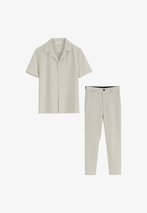 Chemise à manches courtes beige clair avec un col et un pantalon slim assorti, présentant une ceinture noire et sans motifs visibles.