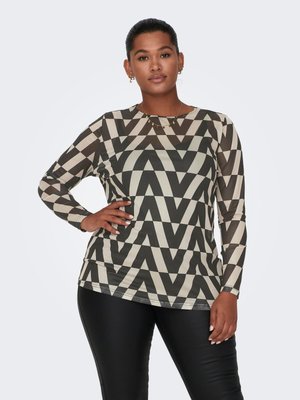 Top de manga larga con patrón geométrico en zigzag en negro y crema; hecho de una tela suave. El modelo lo combina con pantalones ajustados negros.