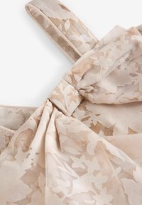 Light beige dress with floral pattern; made of soft fabric, featuring a bow detail at the waist and a textured surface.