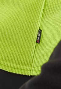 Fleece pullover in bright green with a textured ribbed pattern. Features a black Polartec tag on the side.