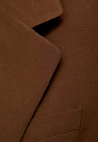 Tessuto per abito marrone caratterizzato da una texture liscia, con rever sovrapposti e un dettaglio sulla tasca. Il materiale ha una leggera lucentezza e una trama fine.