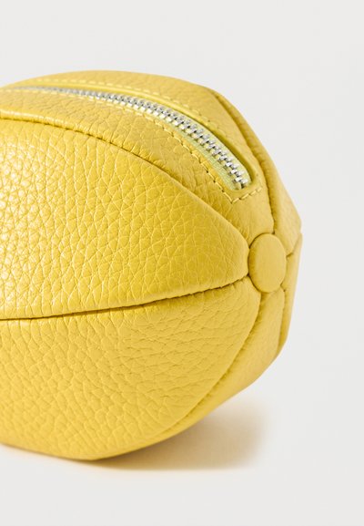 Pochette en cuir texturé jaune en forme de ballon de basket avec une fermeture éclair argentée sur le dessus et un détail bouton sur le côté.