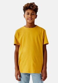 Gul bomullst-shirt med rund hals, korta ärmar och rak passform. Har en liten logotypetikett vid fållen.