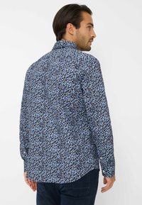 Camicia a maniche lunghe con un motivo astratto blu e nero, colletto a bottoni, vestibilità rilassata e orlo curvo.