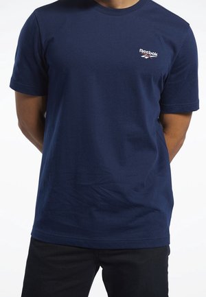 T-shirt in cotone blu navy con maniche corte, caratterizzato da un piccolo logo Reebok bianco e rosso sul petto a sinistra. Texture liscia, vestibilità classica.