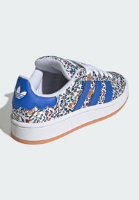 Sneakers med blommönster, vit läderöverkonstruktion, blå syntetiska ränder, vågiga blå detaljer, vita skosnören och gummisula.