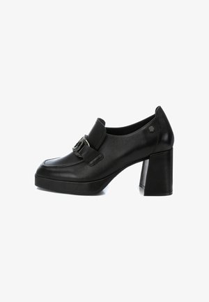 Zapatos de tacón alto de cuero negro con puntera redondeada, panel frontal plano, hebilla decorativa y tacón ancho tipo bloque. Superficie texturizada.