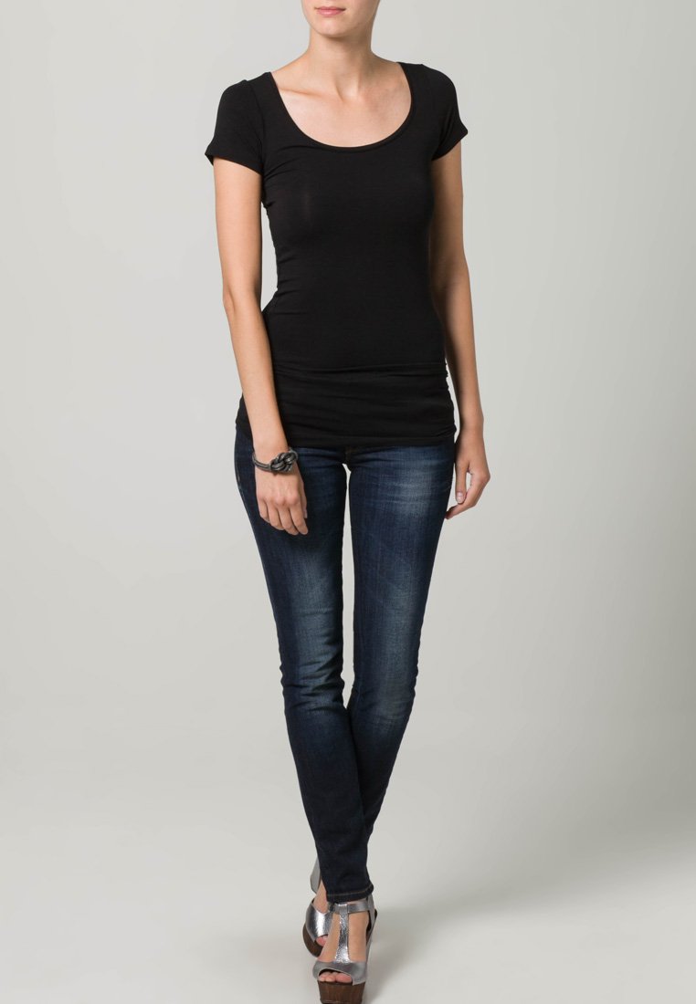 Fekete, testhezálló póló rövid ujjal, sötétkék skinny farmernadrággal párosítva. Ezüst, pántos szandálok és fekete karkötő egészíti ki a szettet.