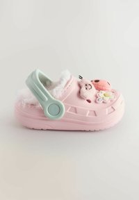 Rosa Plastik-Clog mit flauschiger Fütterung, verstellbarem grünen Riemen, floralem und tierischem Gesichtsschmuck, strukturiertem Sohlen und Belüftungslöchern.