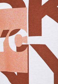 Bílý tričko s velkým hnědým a třpytivě růžovým nápisem, vystihujícím výrazné geometrické tvary a textury.