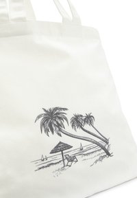 Weiße Leinenshopping-Tasche mit einem schwarzen Grafikdesign von Palmen, einem Strandstuhl und einem Sonnenschirm am Ufer, mit Segelbooten im Hintergrund.