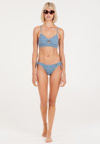 Mėlynas raštuotas bikini kostiumėlis su pynimo dizainu, kuriame yra raktų skylutės detalė viršuje ir šoninio surišimo detalė apačioje. Lygus audinio paviršius.
