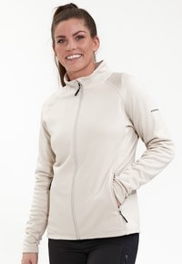 Ljusbeige zip-up-jacka gjord av mjukt fleece; har hög krage, sidofickor med dragkedjor och elastiska ärmslut.