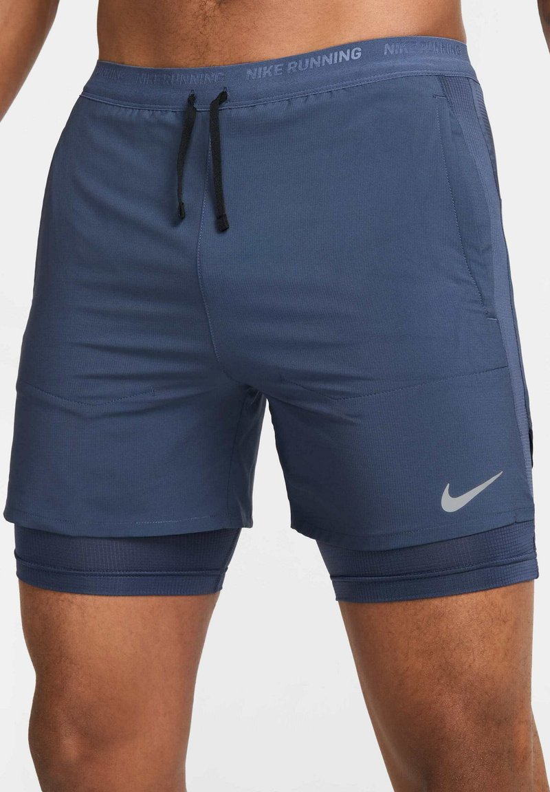Pantalones cortos para correr Nike de color azul marino con cinturilla elástica, cordón de ajuste, bolsillos de malla y forro interior, que presentan un logo reflectante en el costado.
