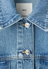 Light blue denim jacket collar and upper front with metal buttons and visible MNG brand label inside.