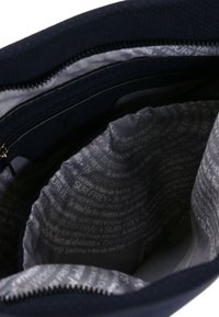 Borsa in tessuto color navy con chiusura a zip, caratterizzata da un interno grigio foderato con motivi di testo ripetuti, texture liscia e tasca interna.