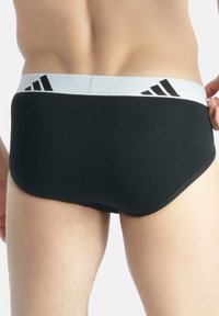 Schwarze, enge Unterwäsche mit einem weißen elastischen Bund, der mit schwarzen Logostreifen versehen ist. Glattes Material und enganliegende Passform für mehr Komfort.