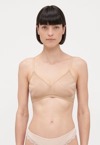 Beige bralette, mis smooth kangast, kolmnurkse disainiga, õhukeste õlgadega ja pehme aluspõhjaga. Polsterdust ega metallosi ei ole nähtav.