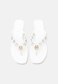 Λευκά σανδάλια με επίπεδη σόλα, με λουράκια με κυκλικά κοψίματα και χρυσά μετάλλια λογότυπου στα δάχτυλα, σε απλό λευκό φόντο.