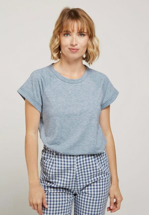 T-shirt bleu chiné avec un col rond et des manches courtes roulées, associé à un pantalon à carreaux bleu et blanc. Texture de tissu douce.