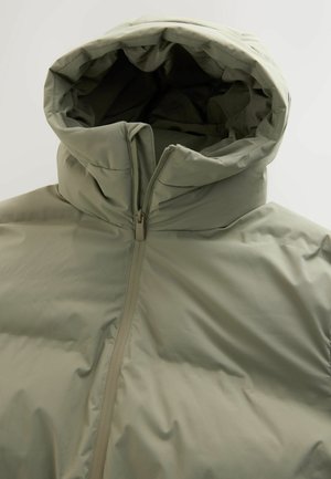 Hellgrüne Pufferjacke mit hohem Kragen und Kapuze. Verfügt über einen zentralen Reißverschluss und eine glatte, gesteppten Textur. Minimalistisches Design.